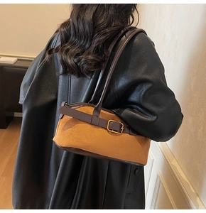 Detail view of vintage brown suede shoulder bag with leather contrast and buckle strap