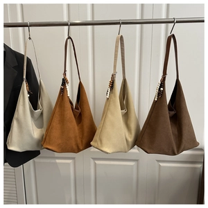 Detail of four large tote bags in neutral colors with wooden bead charms on a white door
