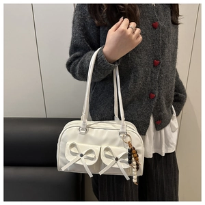 Close-up of white bowling bag with bow-knot pockets and decorative wooden bead charm