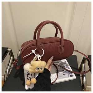 Bordeaux red pillow bag detail with plush bear charm and removable shoulder strap