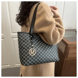 Sac fourre-tout noir à motif M présenté par un mannequin en manteau de laine