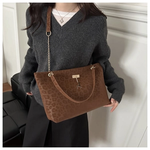Sac cabas léopard marron avec chaîne dorée et pendentif porté par un mannequin