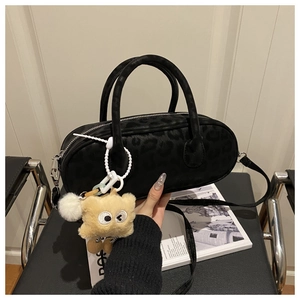Detail of black leopard print pillow bag with fluffy monster charm and shoulder strap