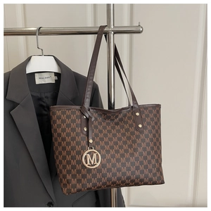 Detail of monogram jacquard tote bag with leather handles and gold M pendant