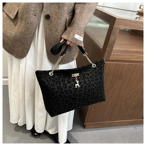 Détail du sac cabas léopard avec une bandoulière en chaîne dorée et un pendentif de cerf