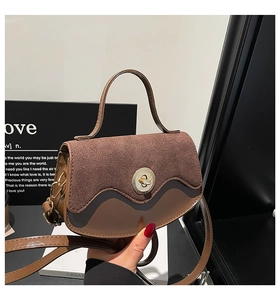 Dettaglio borsa vintage in pelle marrone con patta in camoscio e chiusura dorata