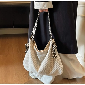 Detail of cream corduroy hobo bag showing woven shoulder strap and textured fabric