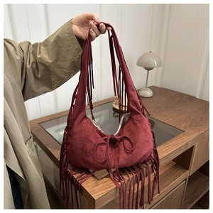 Gros plan d'un sac hobo en daim bordeaux avec des franges décoratives et des glands
