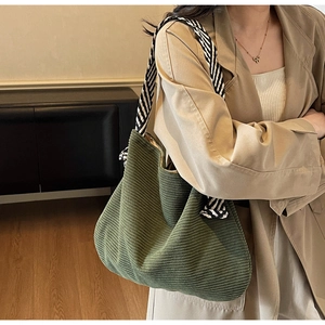 Dettaglio borsa hobo in velluto a coste verde oliva con tracolla a righe sulla spalla