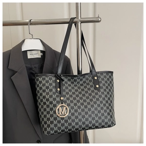 Detail of vintage monogram tote bag with a golden M charm and leather shoulder straps