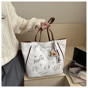 Detail of white canvas tote bag with graffiti art and brown leather handles in a lifestyle setting