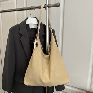 Large beige suede tote bag with decorative wooden beads on a shoulder strap