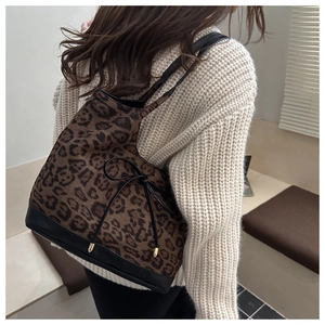 Détail du sac cabas léopard avec bandoulière noire et nœud décoratif aux détails dorés