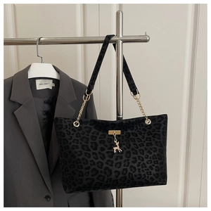 Détail d'un sac cabas léopard avec chaîne dorée et pendentif cerf sur un blazer gris