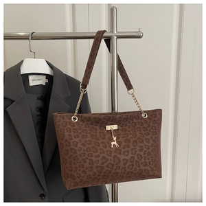 Détail du cabas léopard avec breloque cerf dorée et bandoulière en cuir et chaîne