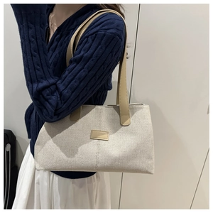 Detail view of cream canvas tote bag with khaki leather handles and contrast stitching