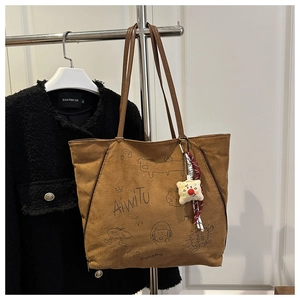Detail view of large brown tote bag with cartoon prints and star plush charm accessory