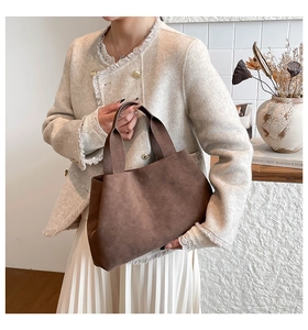 Chic brown suede tote bag held by model in cream tweed jacket and white pleated skirt