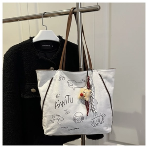 Detail of white canvas tote with cartoon illustrations and brown leather straps