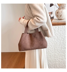 Macro detail of dark brown suede tote bag with matte texture and wide handle design