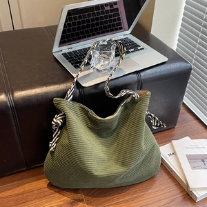 Large forest green corduroy tote bag with zebra print strap on a wooden floor