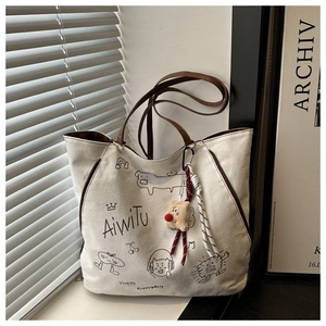 Détail du sac fourre-tout en toile avec illustrations noires et charm ours en peluche