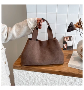 Detail of dark brown suede tote bag with wide integrated handle and spacious retro design