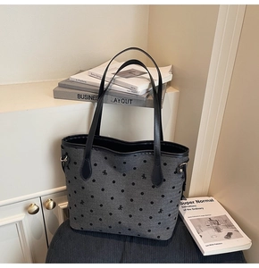 Detailed macro shot of grey tote bag fabric with black polka dots and bow embroidery