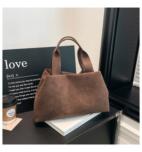 Detail of dark brown suede tote bag featuring a wide handle and minimalist retro design