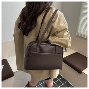 Detail shot of a dark brown vintage tote bag worn by a model in a minimal indoor setting