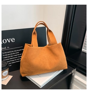 Close-up of high-quality orange suede bucket bag with wide top handles on office desk