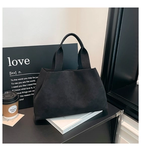 Close-up of black matte suede tote bag with thick strap on a stylish minimalist desk