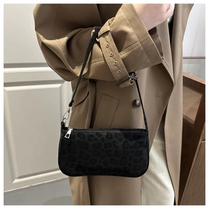 Detail of black leopard print shoulder bag with silver zipper on beige trench coat