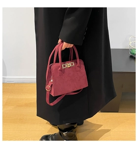 Detail of burgundy suede tote bag featuring golden twist lock and round top handles
