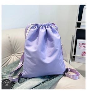 Detailed view of a lilac drawstring backpack on a sofa with smooth satin finish texture