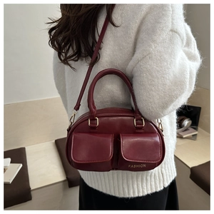 Detail of burgundy leather handbag with dual front pockets and fashion print