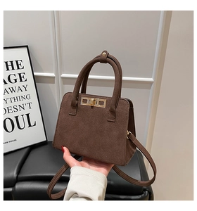 Detail of deep brown suede handbag with golden metal twist lock and textured finish