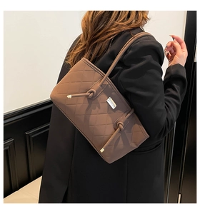Detail of coffee brown quilted shoulder bag featuring classic diamond stitching and metal logo