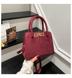 Detail of burgundy suede tote handbag with elegant gold clasp and sturdy top handle
