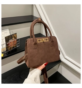 Detail of dark brown suede handbag featuring a gold rectangle twist lock and smooth texture