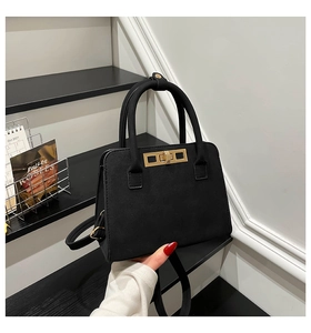Detail of black suede handbag showing high-quality gold rectangular metal twist lock