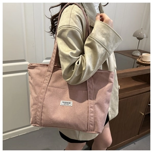Pink corduroy tote bag detail showing large capacity design and white woven label
