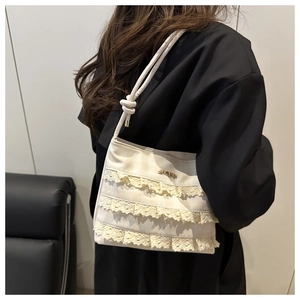 Detail of cream lace tote bag featuring elegant ruffled layers and knotted shoulder strap