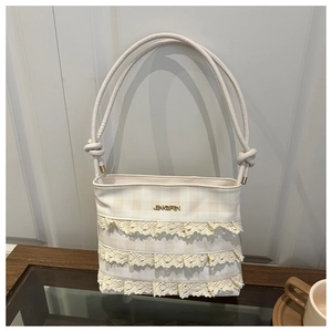 Detail of sweet cream-white lace layers and gold logo on the trendy crossbody square bag