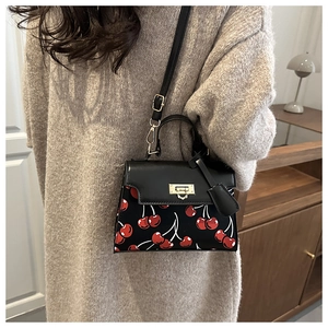 Detail of vintage black bag with cherry print, gold clasp and adjustable shoulder strap