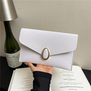 Elegant white Saffiano envelope clutch bag with oval gold buckle in lifestyle setting