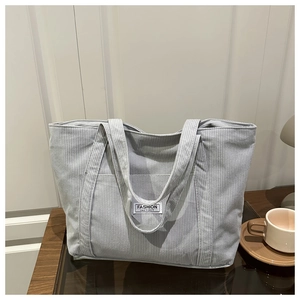Macro detail of soft light blue corduroy tote bag showing the Fashion Instinct label