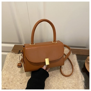 Detail view of caramel brown crossbody bag with gold buckle and adjustable strap