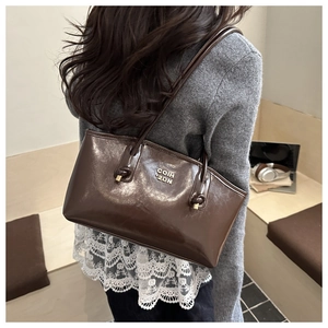 Deep brown leather shoulder bag shown on model in a cozy cafe setting for size reference