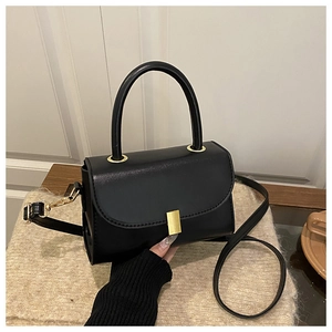 Close-up of black glossy leather crossbody bag featuring a minimalist gold buckle